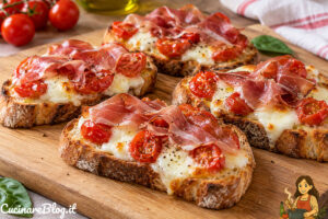 Crostoni con speck e mozzarella filante e pomodorini datterini su pane croccante